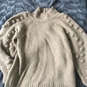 Stickad tröja - Jättemysig stickad beige tröja från Vero Moda. Polokrage samt ”knappdetaljer” längs ärmarna. 