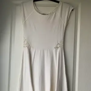 En vit klänning med spetsdetalj, lite volangliknade nertill. Ryggen är helt i spets.  Väl använd men är i fint skick.  