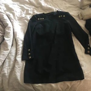  - Säljer mina jättefina svarta klänning med guldknappar längst ned på armen & vid vid axlarna typ ( se bild ) storlek S passar även XS 