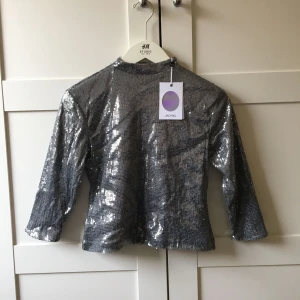 - Topp med små täta paljetter, köpt på Monki för 300kr. Kortare modell med liten ståkrage. Dragkedja i ryggen. Saknar någon enstaka paljett. Ej använd, lappar kvar. 