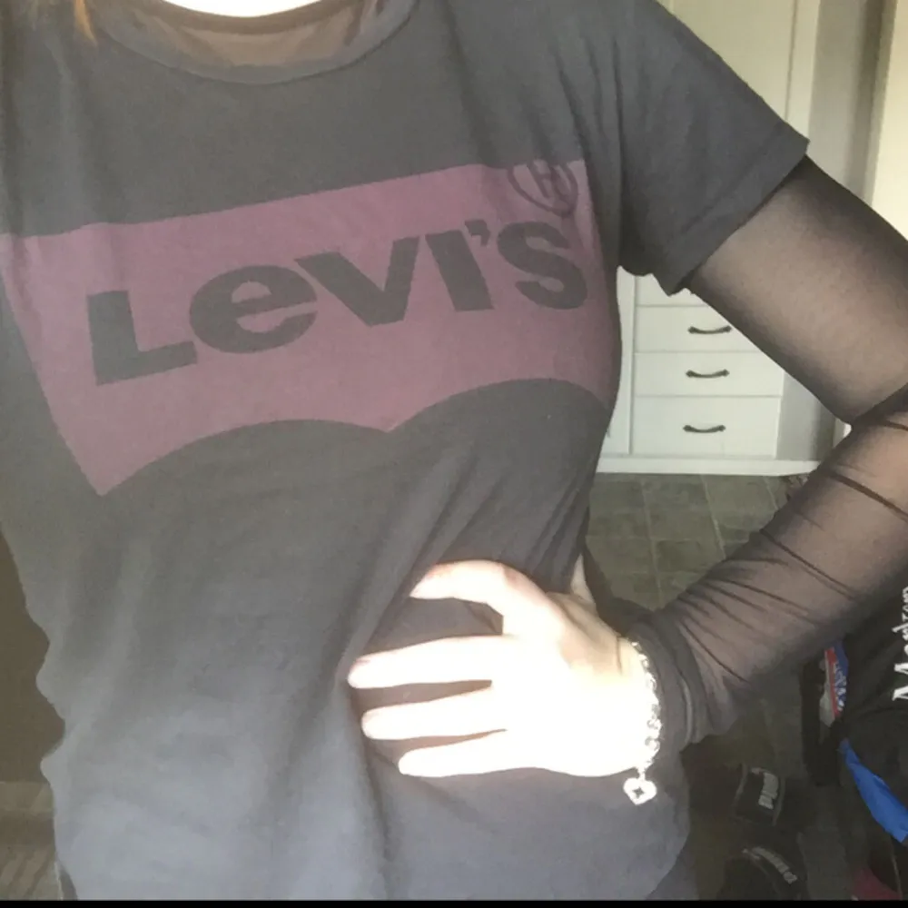 Levis T-shirt. Grå/svart med ett lila Levis märke. Endast använd någon gång då det inte är min stil. Mkt bra skick! Frakt står köparen för (ca 40 kr) . T-shirts.
