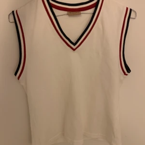 vit väst från sand - jättefin vintage väst från sand!! vit med blå och röda detaljer. västen är märkt som en L men jag skulle själv säga att den är en M. hör jättegärna av dig vid frågor eller intresse!! frakt tillkommer<3