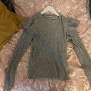  - En grå tröja från zara med volanger på axlarna 