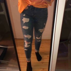  - Hollister super skinny jeans med slitningar. Storlek 26 i midjan men väldigt stretchiga så passar även 27. Dom har snygga slitningar vid ankeln och är extremt sköna. Använt 2 gånger så praktiskt taget nyskick.   Köparen står för frakt
