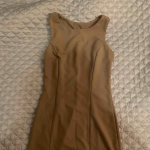  - Beige bodycon klänning i stretch material. Klänning slutar vid låren. Inköpt utomlands och använd ett fåtal gånger. 