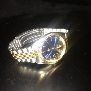 Origo herr klocka - Säljer då det var en present till min pojkvän men den passade tyvärr inte. Klockan fungerar super och är i nyskick. Märke Origo. Klockan har ett silver och guld färgat armband. Urtavlan är navy (mörk blå) med markeringar. Spännet är ett viklås.