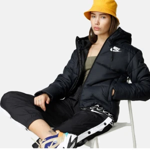 Nike jacka-NSW syn fill HD - Snygg jacka från Nike med luva och resår i nederkant för att hålla värmen. Ett litet hål som lagats av skräddare på ryggen i nederkant. Ordinarie pris 1099 kr