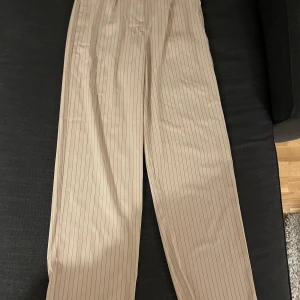 Beiga byxor - Beiga vida byxor med smala svarta streck på från nakd. Jag kan inte ta bild då dom inte passar mig längre. Frakt ingår