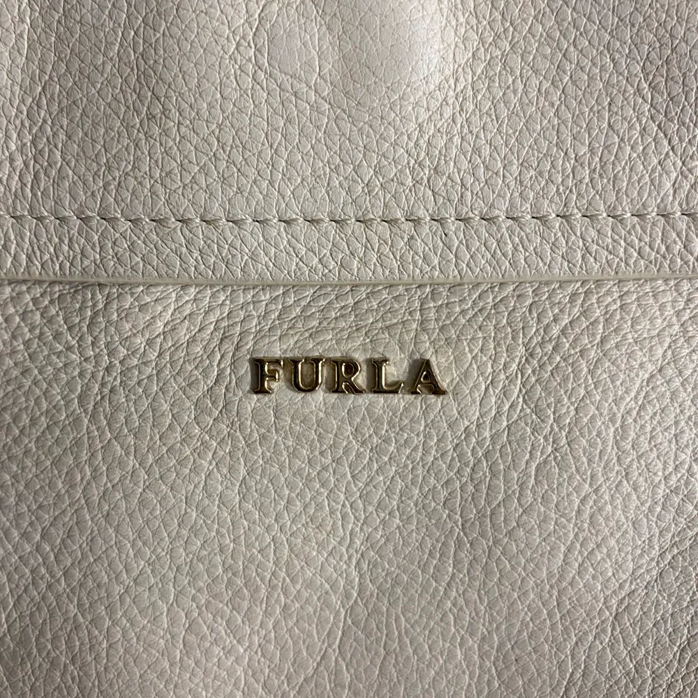 En vit läder väska från Furla som jag har använt väldigt mycket men den har kvar att ge. En cross body messenger väska med rem och gyllene detaljer. Väskor.