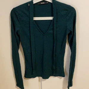 Mörk grön  - En mörk grön tunn stickad tröja med snören 