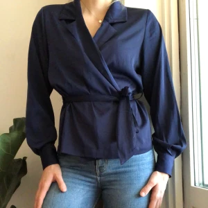Knytblus i satin från bikbok - Stilfull knytblus i marinblå satin från bikbok. Klädda knappar vid handlederna. Tveka inte att höra av dig vid frågor, funderingar eller önskemål🌟 frakt tillkommer🌼