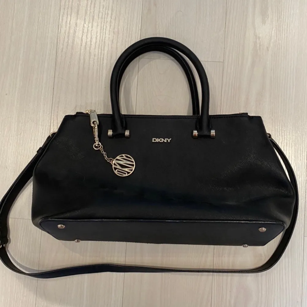 Purse/handbag from DKNY. Black with gold details. Never worn and in perfect conditions. Spacious inside, wearable over the shoulder with the longer strap or held in the shorter handles. Shipping is included in the price!💞. Väskor.