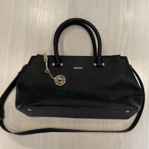 DKNY handbag  - Purse/handbag from DKNY. Black with gold details. Never worn and in perfect conditions. Spacious inside, wearable over the shoulder with the longer strap or held in the shorter handles. Shipping is included in the price!💞