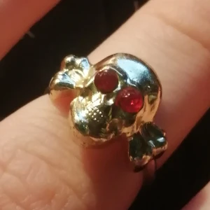 Ring med döskalle med rubiner - Söt liten ring med guldig döskalle med rubiner till ögon. Kan sitta på lillfingret eller högre upp på långfingret😁 frakt ingår🥰