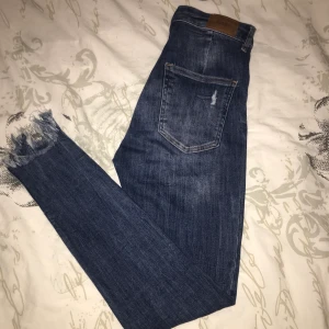 Jeans med slitningar - Högmidjade jeans i storlek 26/30, jeansen är i stretchigt material så den passar även större storlekar.