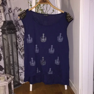  - Marin blå tröja från diables med guldiga nitar på axlarna och kronor på framsidan
Något nopprig, inte något som stör
Ny pris 200kr