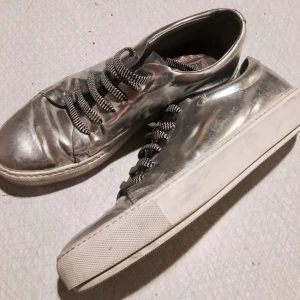 - Silvriga sneakers från acne, använt max 5gånger. Medföljer små silvriga plattor med smilies på som man fäster på snörningen, samt vanliga vita skosnören. 