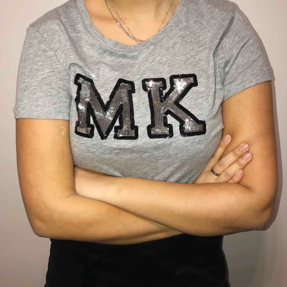 Snygg grå Michael Kors t-shirt med paljetter. Oanvänd, endast testad på bilden. Storlek L men passar en storlek M bättre. Köpt för 1000 kr.. T-shirts.