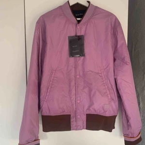  - ACNE STUDIOS MILLS FACE LILAC PURPLE  Vändbar bomber/baseball-jacka från Acne Studios. Aldrig använd. Face-logga i höger nederkant ovanför mudd.   Nypris runt 3000 kr. 
