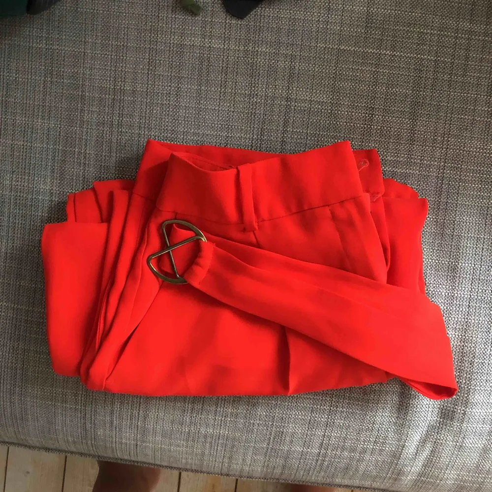 Röda kostymbyxor med tillhörande midjeband. Köpta för 500 kr. Vida ben men tajt midja. Figurnära passform. Jeans & Byxor.