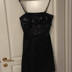  - Vacker festklänning endast använd två ggr. Storlek XL. Svart med paljetter och rosett i byst, stenar i axelband och med tyll underkjol för vackert fall. 