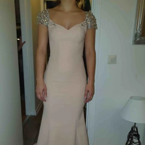  - Klänning med detaljer vid armarna. Ryggen har extra tyg som är syd som kan tas bort vid köp. 