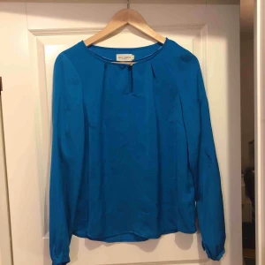  - Turkos siden blus från Holly&Whyte (Lindex) Storlek 36 mycket använd. Säljs billigt pga hål i ärmen.  