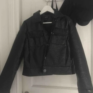  - Säljer min jacka från lindex! Har använt den en gång i våras. Mycket bra skick.  Materialet är lite speciellt, la in en bild med blixt för att man ska se lite tydligare vad det är för material. Jackan har stora silvriga knappar.  Köparen står för frakt! 