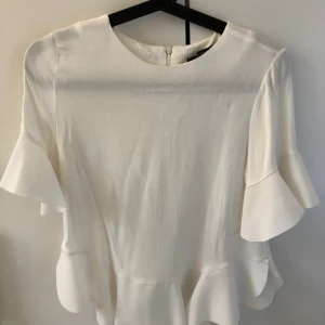  - Vit blus med volang på ärmarna samt nertill. Använd ett fåtal gånger så den är som ny.  Fraktar, köparen står för frakten 
