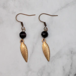  - Bronsfärgade örhängen med glaspärlor och löv/fjäder. Nickelfria. Fri frakt vid köp över 100:-.