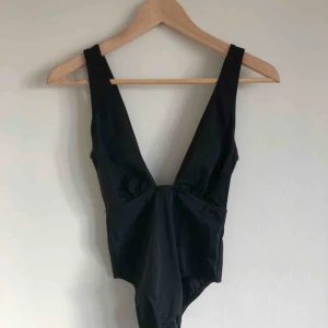  - Snygg, svart baddräkt från asos.  Djupt skuren både fram och bak men med vanlig skärning nertill.  Aldrig använd.  Frakt inkluderad 
