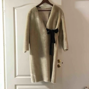  - Väldigt fin fuskpäls kappa. Beige. Svart knyte. Ficka på varsin sida. Storlek XS men passar även S. Oanvänd med prislapp kvar.  Nypris: 799kr 