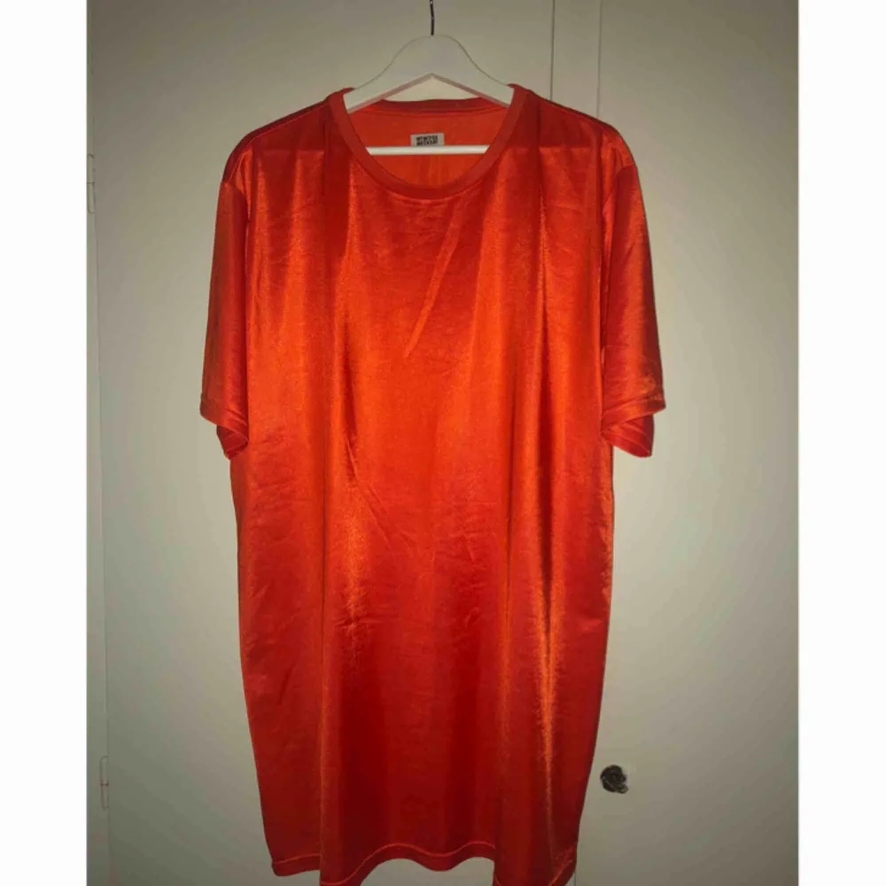 Orange (ser lite mörk ut på bilderna) stor tisha/t-shirtklänning i glansigt material. Använd 1 gång! Frakt tillkommer.. Klänningar.