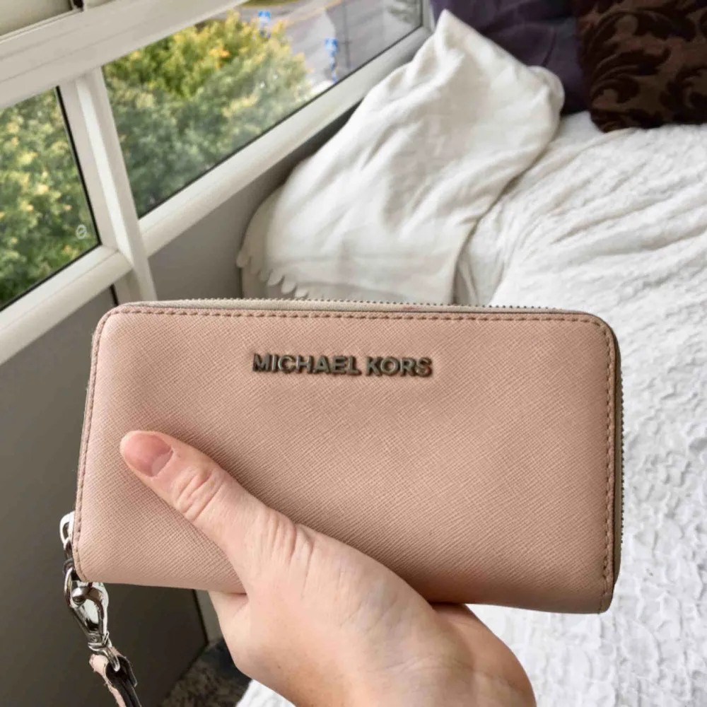 Hudfärgad jetset Michael kors plånbok, köpt för 1500 kr. Bra skick på ”skinet” ser den ut som helt ny. Tar ett lågt pris då metalldelarna lite är ”blekta” då jag haft den mkt utomlands i sol och nära saltvatten.. Accessoarer.