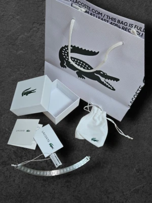 Silver Lacoste armband  - Helt ny Silver Lacoste Armband ⬇️ 💎  ⚡️ Skickas inom 24h/ direkt ⚡️ 📦   Included in the package: ✅ Original Lacoste Box ✅ Lacoste Shopping Bag ✅ Dustbag ✅ Authenticity Documents ✅ Cards + QR-Kod Scan (Mobile) ✅ Lacoste Bracelet + Tags  Quality: 10/10 no damages, no scratches, brand new ❄️, Stainless Steel (ete) Lenght: 21cm (can be adjustable) 📏   Perfect present for him 🎁 💝   #lacoste #armband #stockholm #danmark #poland #lacostebracelet #bracelet #finland #present #gift