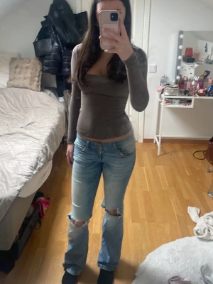 Blå slitna jeans med hål på knäna - Säljer ett par ljusblå jeans med raka ben och slitningar samt hål på båda knäna. Jeansen har klassisk femficksdesign och är tillverkade i denim. Perfekt för dig som gillar en avslappnad och trendig look.