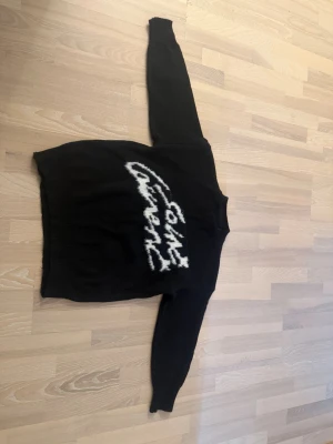 Svart stickad Saint Laurent-tröja - Svart stickad tröja från Saint Laurent med vit fuzzy logga i grafisk stil på bröstet. Tröjan är använd 1 gång tidigare men är för kort. Den är storlek M men är väldigt liten i storlek så om har du storlek S så passar den. Nypriset 945 kr säljs pågrund av felaktig storlek.