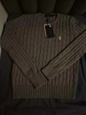 Grå kabelstickad tröja Polo Ralph Lauren - Säljer en snygg grå dam cable knit tröjan från Ralph lauren | I färgen grå med vit logga och storlek S | Helt ny och fräsch | Hör av er för mer information/bilder! 