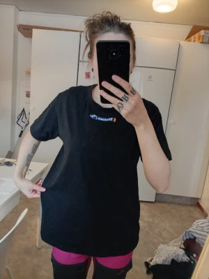 Svart T-shirt  - Svart T-shirt med Tillotek-logga på bröstet. Klassisk rund hals och korta ärmar. Passformen är normal och materialet känns som bomull, perfekt för en avslappnad stil.