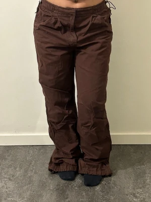 Bruna parachute byxor - Snygga bruna cargobyxor med avslappnad passform och dragsko i midjan. Byxorna har vida ben och resår i midjan för extra komfort. 