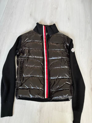 Svart Moncler Cardigan - Tvär fet svart Moncler cardigan. Perfekt för nu för våren och för dig som är grisch och orten. jackan är använd 1-2 gånger senaste veckan då jag fick den