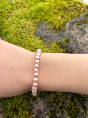 Rosa pärlarmband med elastisk tråd - Snyggt armband med ljusrosa pärlor trädda på elastisk tråd. Pärlorna är runda och har en glansig finish som ger ett stilrent intryck. Perfekt accessoar för att addera lite färg till din outfit.