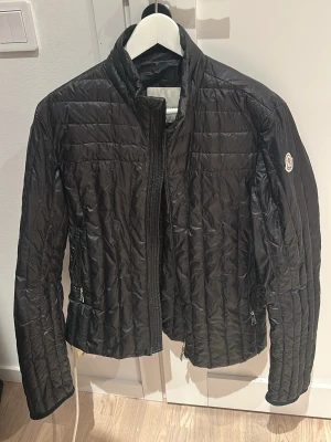Svart dunjacka från Moncler - Säljer en svart dunjacka från Moncler bra skick lite äldre modell och ett litet hål som är täckt med en svart tejpbit men går att sy igen därav priset strlk 1/s