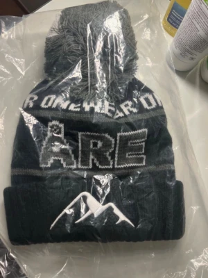 Svart mössa med tofs och Åre-tryck - Säljer en svart stickad mössa från Onewear 'ÅRE' Perfekt för vädret eller en åktur till skidbacken 