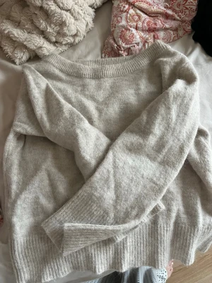 Beige stickad tröja Gina Tricot - Mysig beige stickad tröja från Gina Tricot med rund halsringning och ribbade muddar vid ärmslut och nederkant. Perfekt för lager på lager och enkel att matcha till olika outfits. Tröjan har en avslappnad passform och är gjord i mjukt material. Off-shoulder 