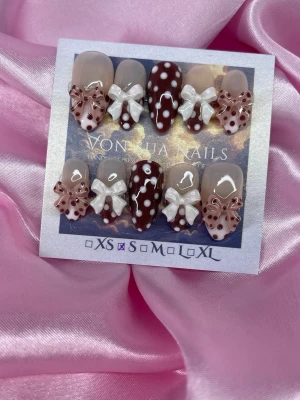 Bambi (S);Medium Almond - Snygga handgjorda press-on naglar i brun och nude med vita prickar och stora 3D-rosetter. Medium mandelform, dekorerade med både glansig finish och detaljerade prickmönster. Perfekt för dig som vill sticka ut med en söt och trendig nageldesign.S: 15 mm, 11,5 mm, 12 mm, 11 mm, 9 mm 