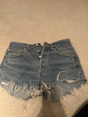 Levi's ljusblå jeansshorts - Säljer ett par klassiska ljusblå jeansshorts som är perfekta för sommaren och ger en avslappnad vintagekänsla.