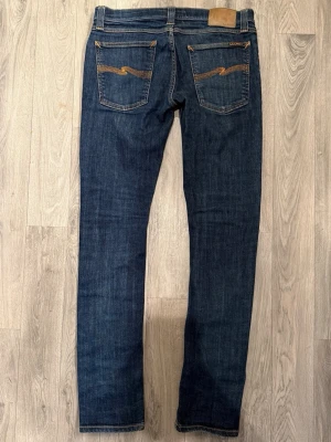 Nudie Jeans Mörkblå Stretch W30/L34 - Slim Fit - Mycket fint skick. Mått - Midja: 40cm, Ytterbenslängd: 102cm, Benöppning: 15,5cm. Modellen är 185cm & 63kg. Hör av dig vid funderingar!🤝