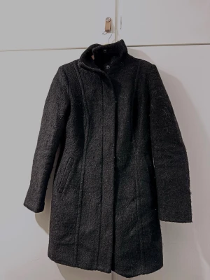 Varm kappa - En svart kappa för höst och vinter. Dragkedja med två knappar längst upp vid hasen. Har lite katthår på sig, men det försvinner ju efter en tvätt… skulle säga att den passar både storlek S och XS beroende på vilken passform man vill ha. Har suttit ganska tight på mig som är 165 cm lång och har breda axlar… Den har tidigare gått upp i sömmarna på insidan så jag har sytt ihop dessa, men inget som varken syns eller stör när man har på sig kappan.