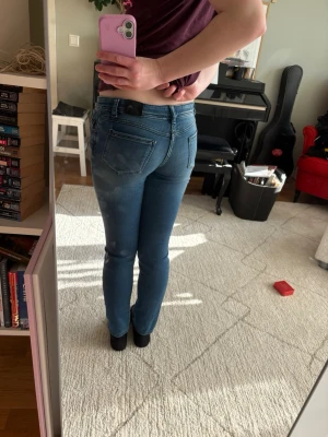 Blå skinny jeans från Tommy Hilfiger - Säljer ett par klassiska blå skinny jeans från  Tommy Hilfiger med snyggt slitna detaljer och fem fickor. Jeansen har normal midja, bälteshällor och är tillverkade i stretchigt denim för en bekväm passform. Bra kvalitet!